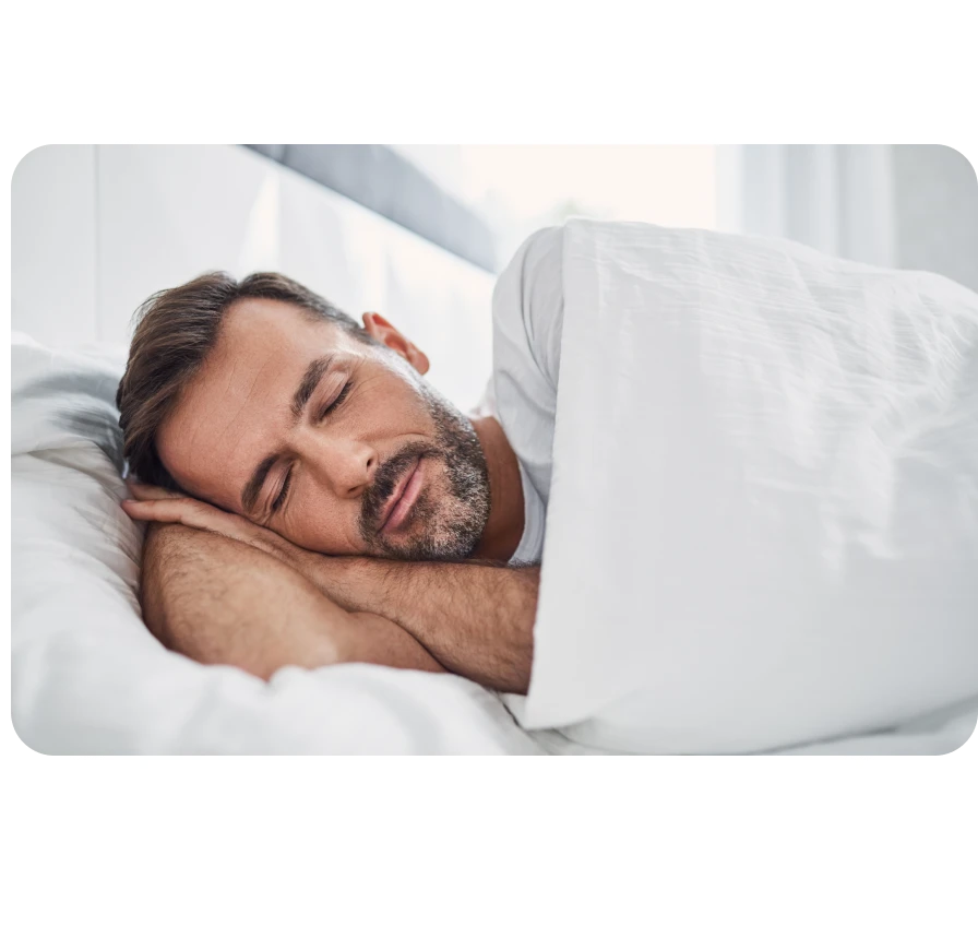 A mature man, looking very relaxed, sleeping in bed.